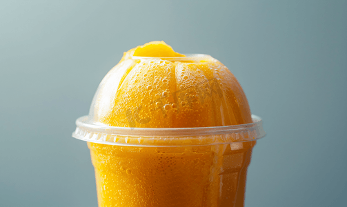 黄色橙子摄影照片_塑料杯中的橙子冰沙
