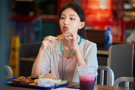 开心的女生摄影照片_在商场快餐厅大吃特吃的中国可爱少女人像