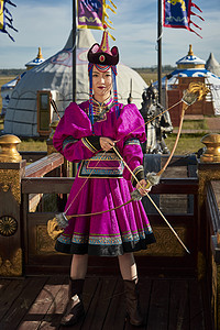 爱神的弓箭摄影照片_蒙古包前身穿蒙古族饰手持弓箭的蒙族少女