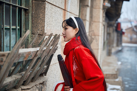眼神放电摄影照片_雪后在老城古巷穿着喜庆服饰的亚洲少女