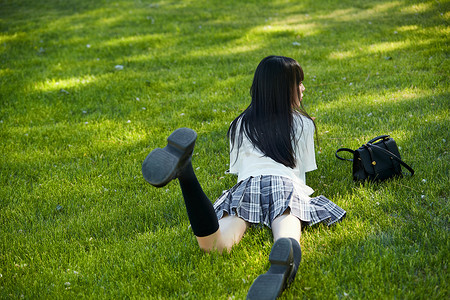 在户外草坪看书学习的女生