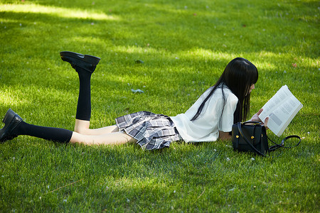 在户外草坪看书学习的女生