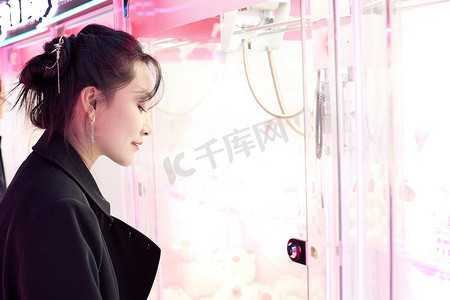 在娱乐城玩抓娃娃机的美女