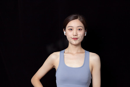 瑜伽动作摄影照片黑色背景穿运动服戴耳机的青年女性