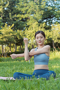 穿着瑜伽服的东方女性在草地上做瑜伽运动