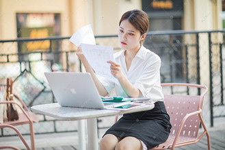 商务白天工作状态中的女职员户外看文件摄影图配图