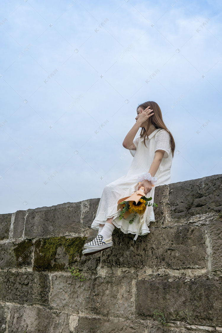 蓝天下坐着撩头发的美女侧面摄影图配图