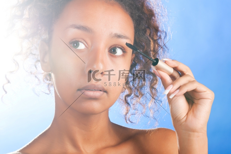 阳光美丽的黑白混血儿妇女正在使用睫毛膏，在天空的背景高清摄影大图 千库网