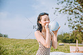 夏天文艺白天穿着长裙的美女草地吹气球摄影图配图