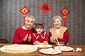 除夕爷爷奶奶教小女孩包饺子摄影图配图