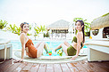 夏日清凉白天两个比基尼美女户外泳池坐着摄影图配图