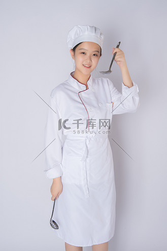 年轻女厨师白天一个女厨师白背景上拿勺子喝汤摄影图配图