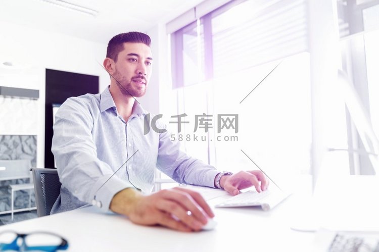 坐在办公桌前的迷人的上班族。坐在办公室办公桌前的年轻商人高清摄影大图-千库网