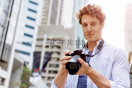 男摄影师在拍照。专业摄影师在城市中拍照高清摄影大图-千库网