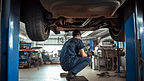 汽车机械师在维修汽车底部零件

