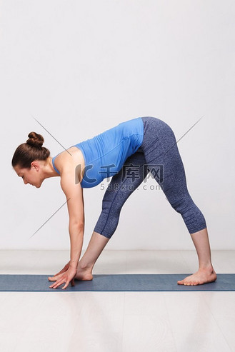 女人做 ashtanga vinyasa 瑜伽体式 parsvottanasana - 在灰色 bagck