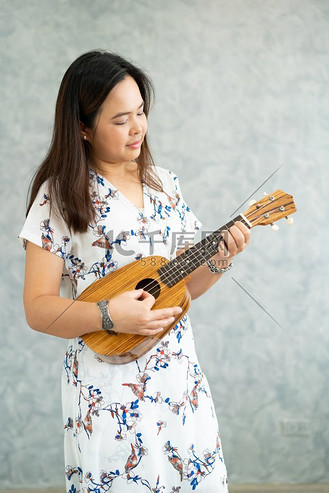 快乐的女音乐家在录音室里弹奏四弦琴和唱歌.吉他贝斯手