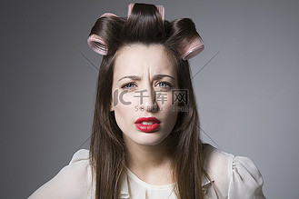 满脸愁容的年轻女子,戴着卷发器,涂着红色口红美女人物特写