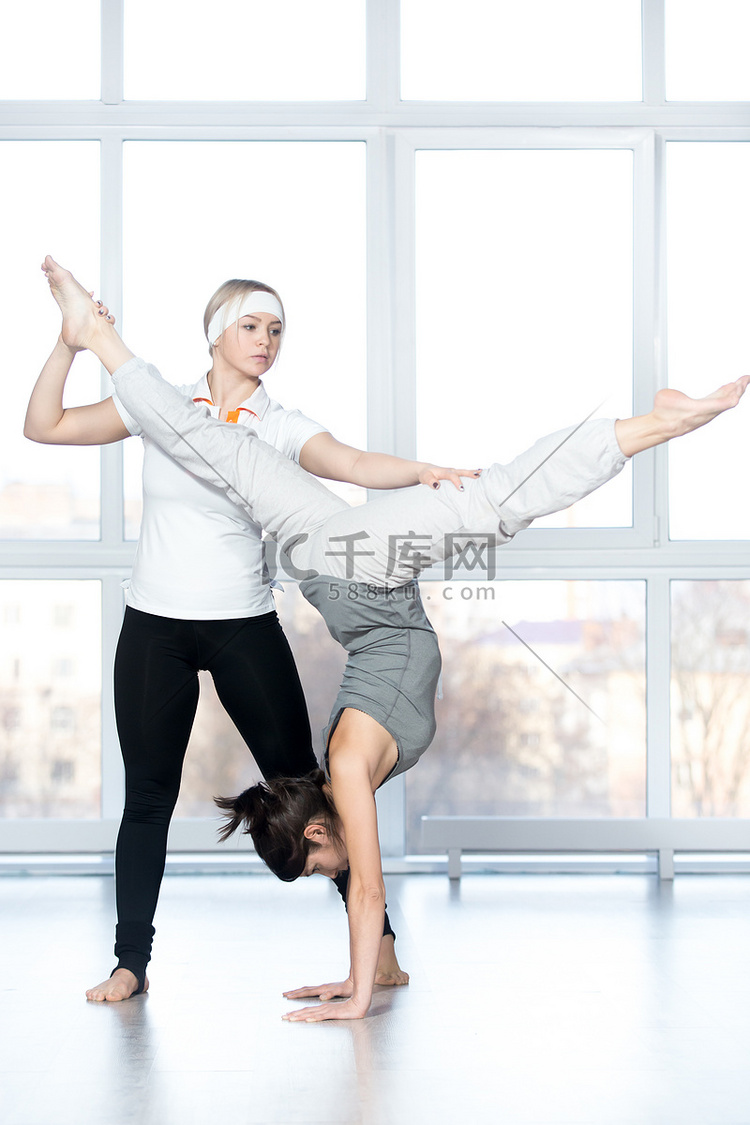 Trainer helping student to do handstand高清摄影大图-千库网