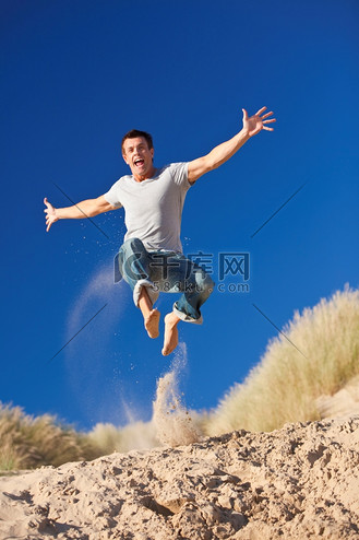 快乐兴奋的年轻人在海滩上跳跃阳光明媚的夏天
