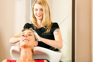 摄影图年轻人在理发店洗头发,理发师正在给他的客户洗头