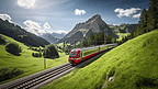 夏天，一列红色的长火车穿过瑞士阿尔卑斯山附近的绿色山谷，