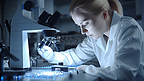 技术人员用显微镜检查印刷电路板上硅片的每个工件，模糊背景，模糊人物

