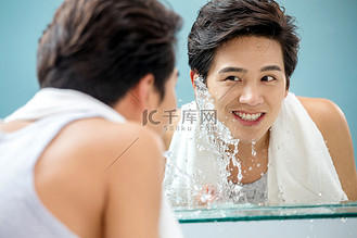 年轻男人对着镜子洗脸