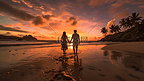 夕阳下沙滩上牵手的情侣