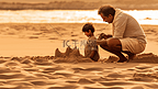 一个男人和一个孩子在海滩上玩沙子