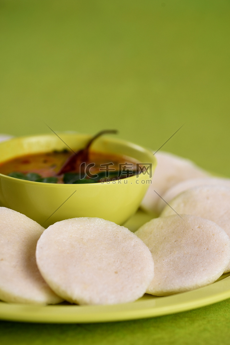 Idli 与 Sambar 在碗中的绿色背景，印度菜：南印度最喜欢的食物 rava idli 或 semolina idly 或 rava ...