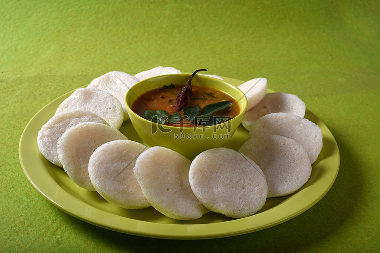 Idli 与 Sambar 在碗中的绿色背景，印度菜：南印度最喜欢的食物 rava idli 或 semolina idly 或 rava ...