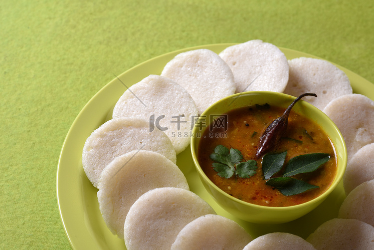 Idli 与 Sambar 在碗中的绿色背景，印度菜：南印度最喜欢的食物 rava idli 或 semolina idly 或 rava ...
