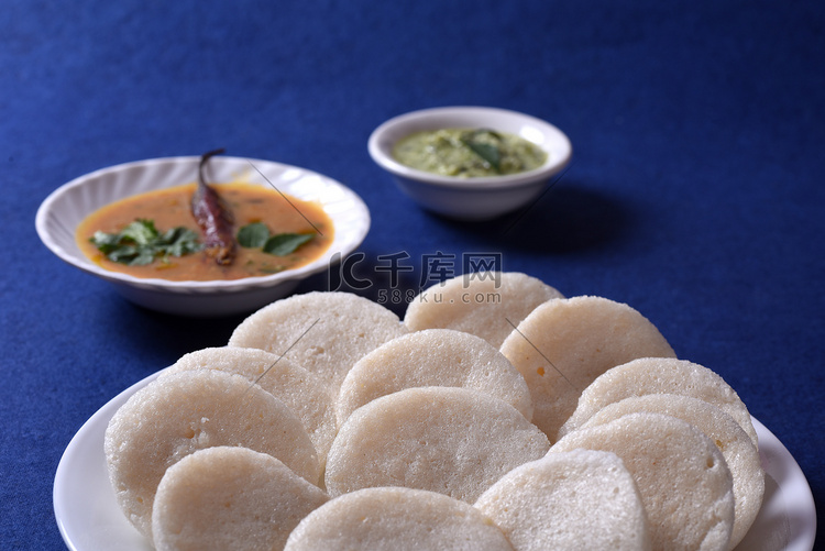Idli 与 Sambar 和椰子酸辣酱在蓝色背景，印度菜：南印度最喜欢的食物 rava idli 或 semolina idly 或 ...