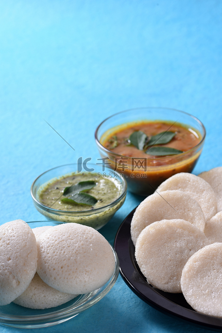 Idli 与 Sambar 和椰子酸辣酱在蓝色背景，印度菜：南印度最喜欢的食物 rava idli 或 semolina idly 或 ...