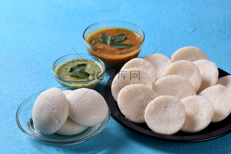 Idli 与 Sambar 和椰子酸辣酱在蓝色背景，印度菜：南印度最喜欢的食物 rava idli 或 semolina idly 或 ...