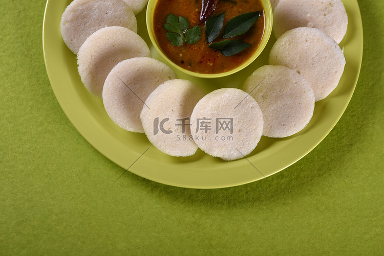 Idli 与 Sambar 在碗中的绿色背景，印度菜：南印度最喜欢的食物 rava idli 或 semolina idly 或 rava ...