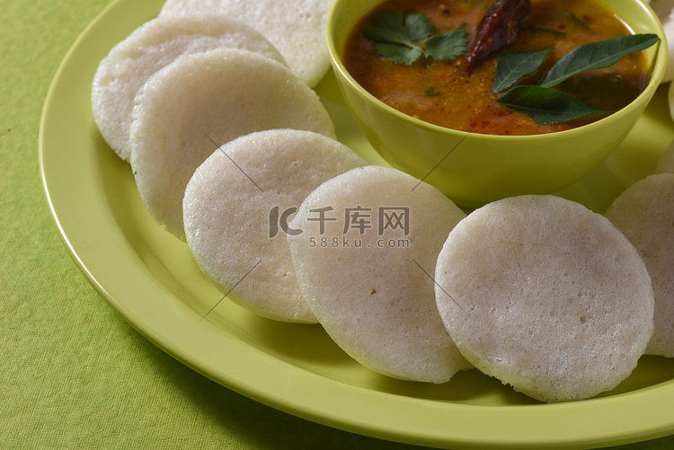 Idli 与 Sambar 在碗中的绿色背景，印度菜：南印度最喜欢的食物 rava idli 或 semolina idly 或 rava ...