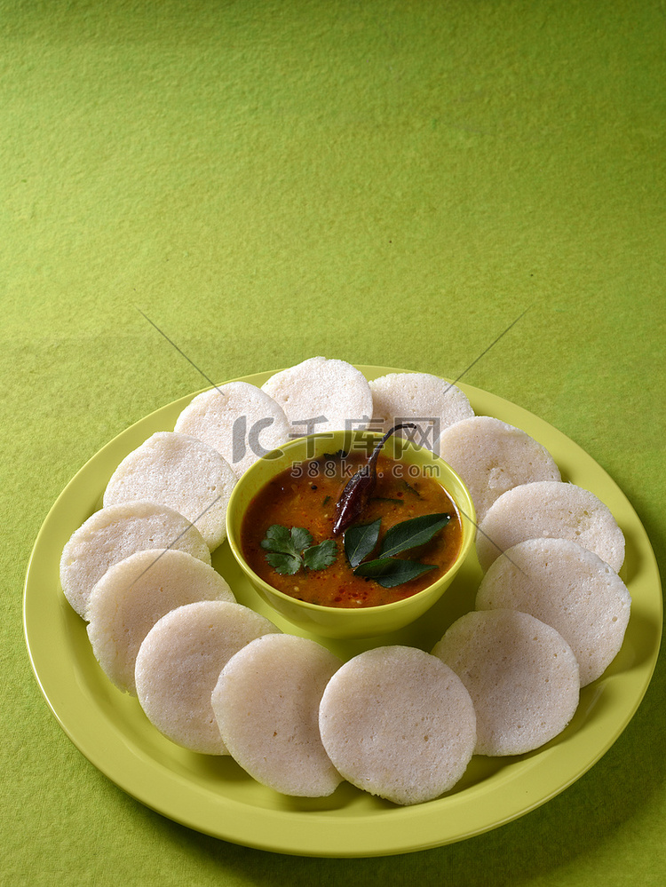 Idli 与 Sambar 在碗中的绿色背景，印度菜：南印度最喜欢的食物 rava idli 或 semolina idly 或 rava ...