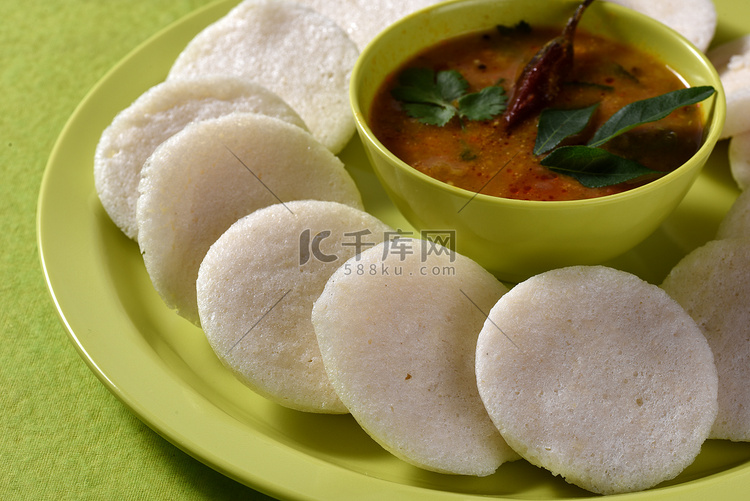 Idli 与 Sambar 在碗中的绿色背景，印度菜：南印度最喜欢的食物 rava idli 或 semolina idly 或 rava ...