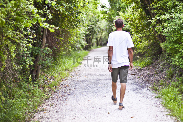 在夏季绿色公园的路径上行走的人。高清摄影大图-千库网