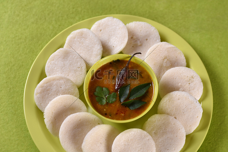 Idli 与 Sambar 在碗中的绿色背景，印度菜：南印度最喜欢的食物 rava idli 或 semolina idly 或 rava ...