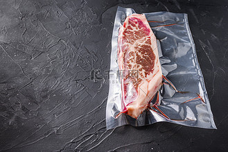 顶级刀片牛排,真空包装的有机牛肉,用于在黑色纹理背景下进行真空烹饪