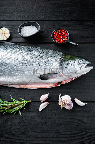 黑色木质表面上的新鲜生鲑鱼红鱼,平躺