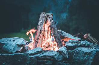 在夏天,森林里用黄色和红色的火焰露营篝火.