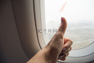手势竖起大拇指,ok 手势,女人的手在飞机上的 window 背景上