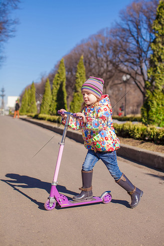 可爱的小女孩在户外滑板车上玩得开心