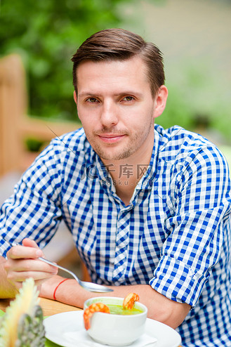 在户外咖啡馆穿着蓝色衬衫的白人年轻欧洲男子.