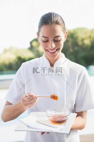 微笑的美容师拿着蜂蜜盘子