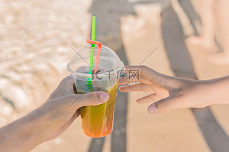 将太无二logo图片素材_在海滩的背景下,男孩的手将一杯彩色的冷冻无